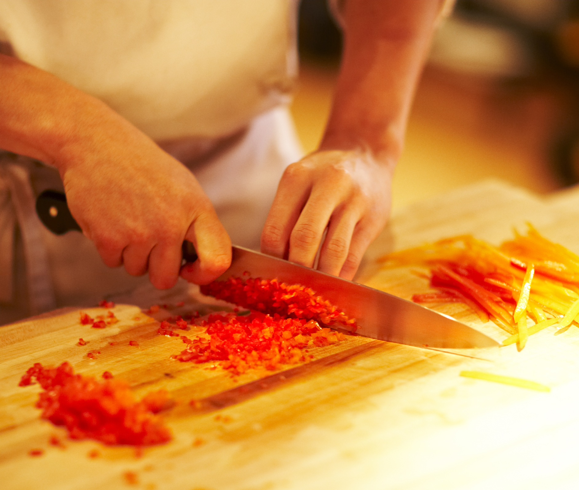 chef mincing bell peppers with knife